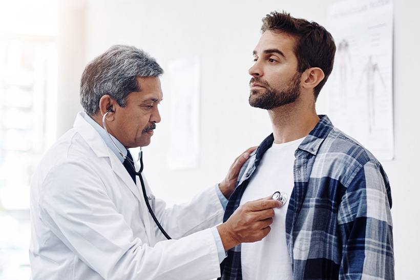 A doctor listens to a patient's chest with a stethoscope during a medical examination